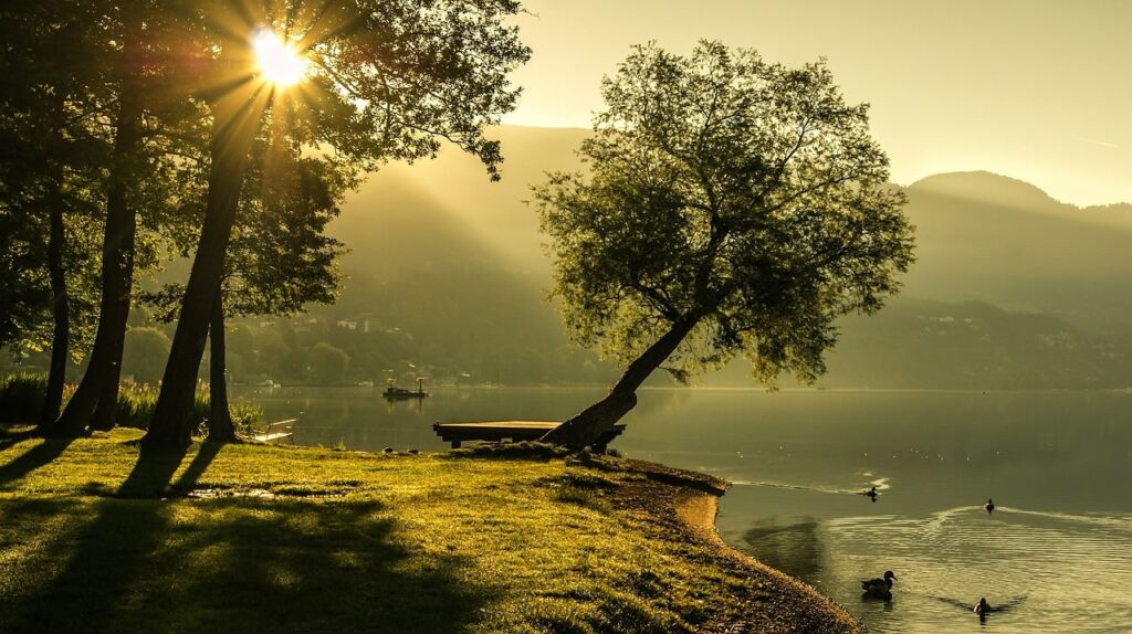 Sun sises in the landscape with mountains and trees near the lake