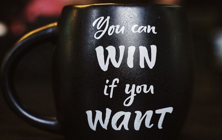 A black colour cup has the message that you can win if you want