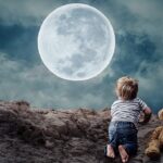 A child having his toy near and seeing the full moon