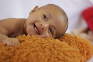 Cute baby with smile A cute smiling baby laying down on soft bed